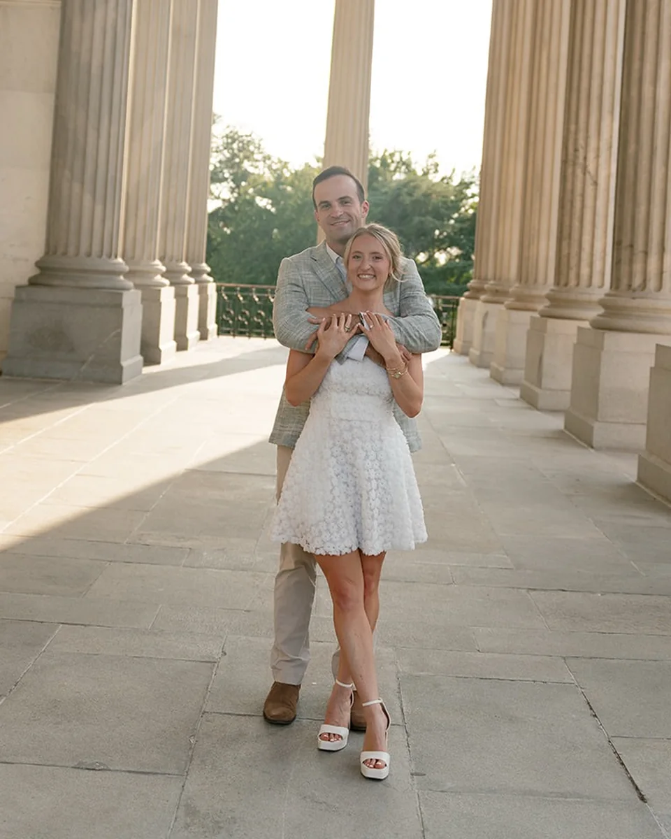 Marcus holding Ellie from behind in the State House colonnade