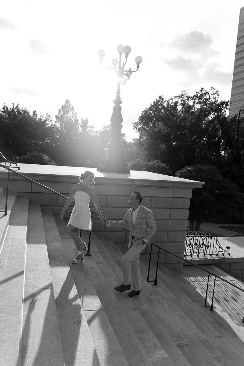 Ellie and Marcus on the State House steps under a lamp post, in black and white