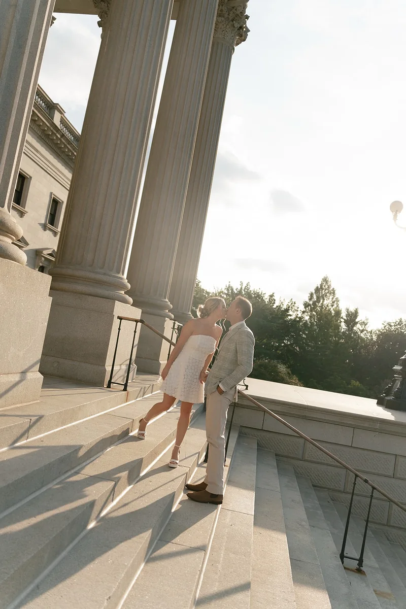 Ellie and Marcus kissing on the State House steps beside the columns
