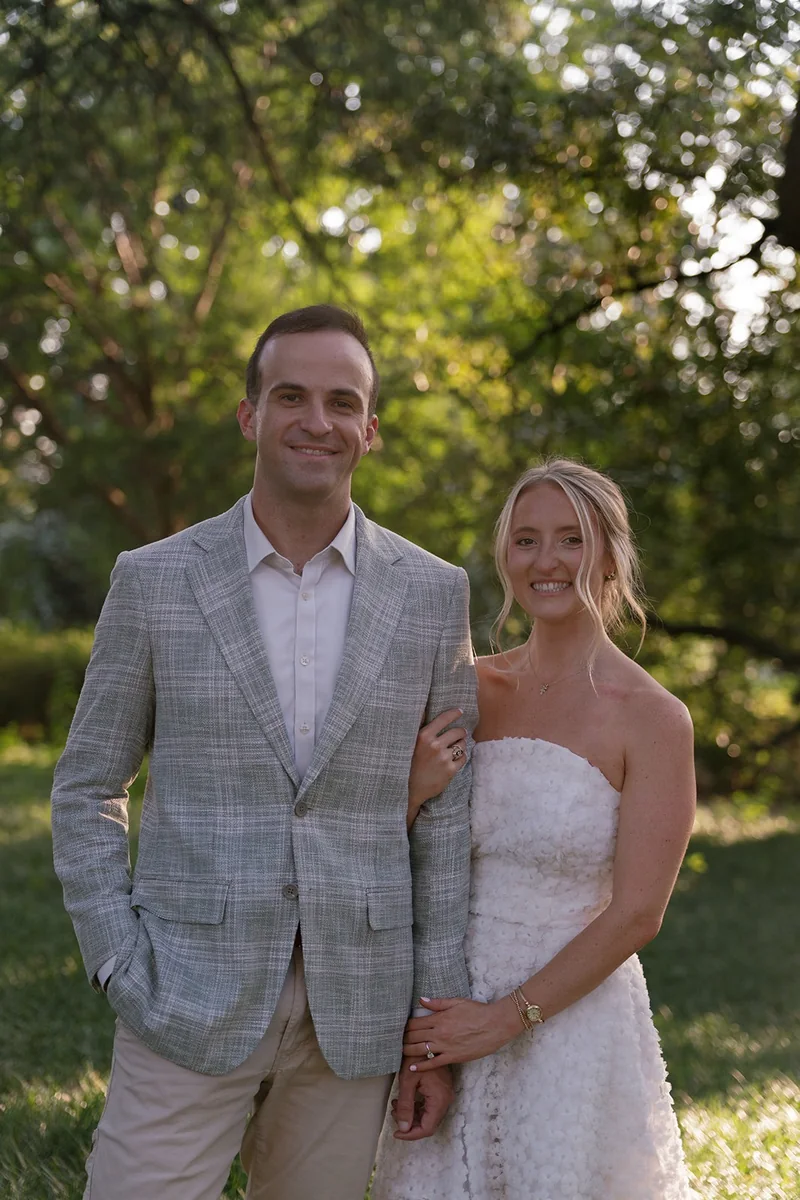 Ellie and Marcus under the trees, smiling at the camera